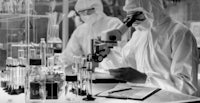 a black and white photo of two people working in a laboratory