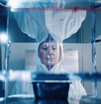 a woman in a white lab coat standing in front of a glass